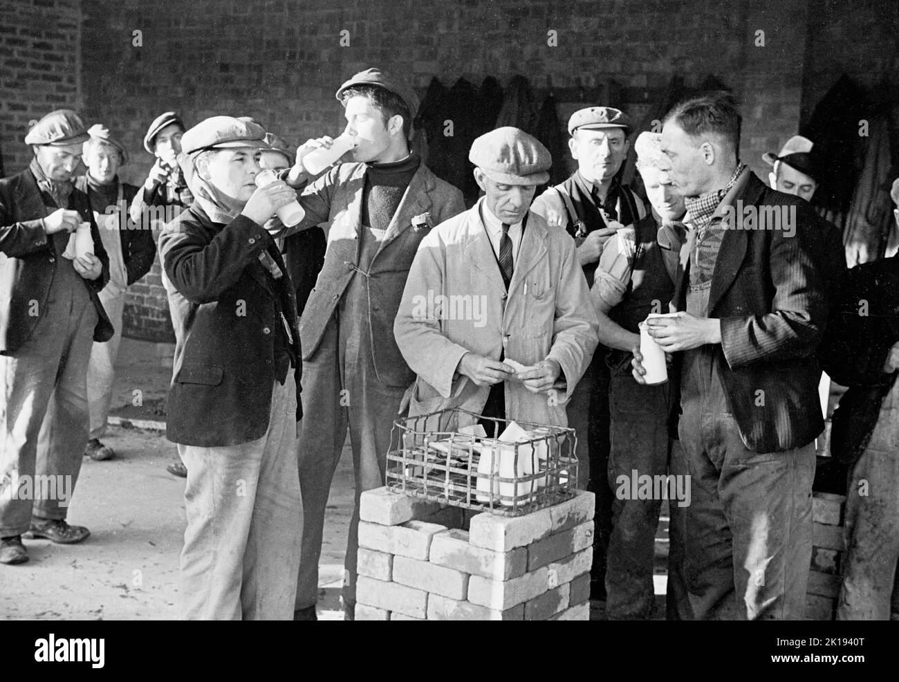 1930s-historical-work-breaksawmill-workers-drinking-bottles-of-milk-in-an-outdoor-yard-of-the-...jpg